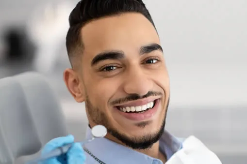 Man smiling in dental chair after cosmetic bonding at Roam Dental