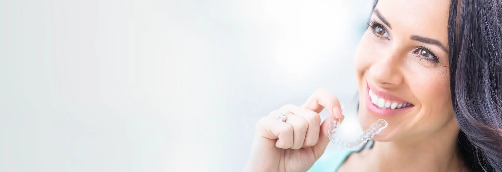 Woman holding Reveal clear aligner showing how it looks